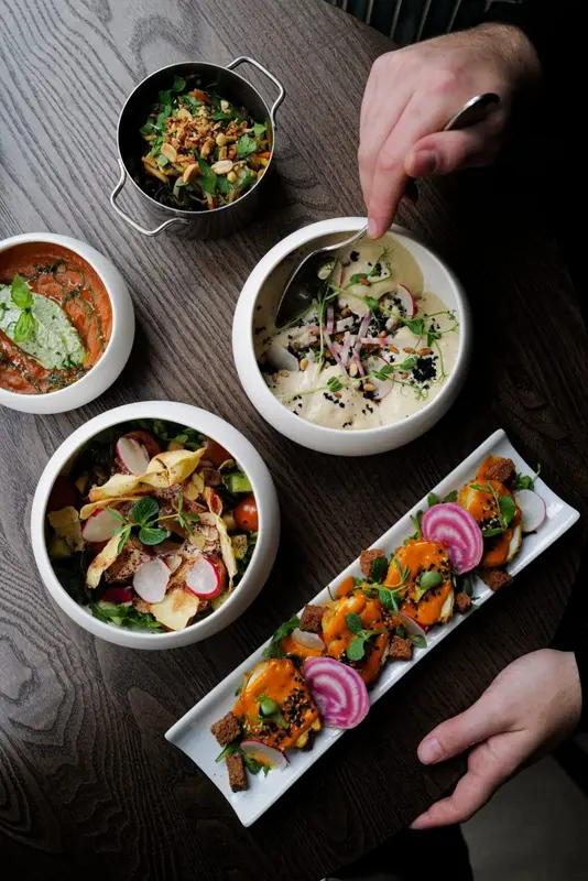Colorful Middle Eastern dishes with radishes, herbs, and sauces served in white bowls at an upscale restaurant