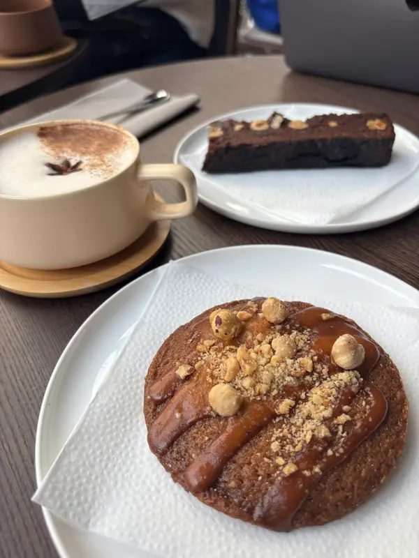 Hazelnut caramel tart and chocolate brownie with cappuccino at a cozy café table