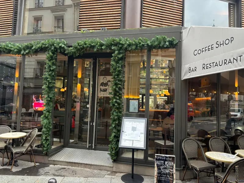 Maison Saint-Martin coffee shop and restaurant exterior with festive garland decor and Parisian bistro chairs in Paris.