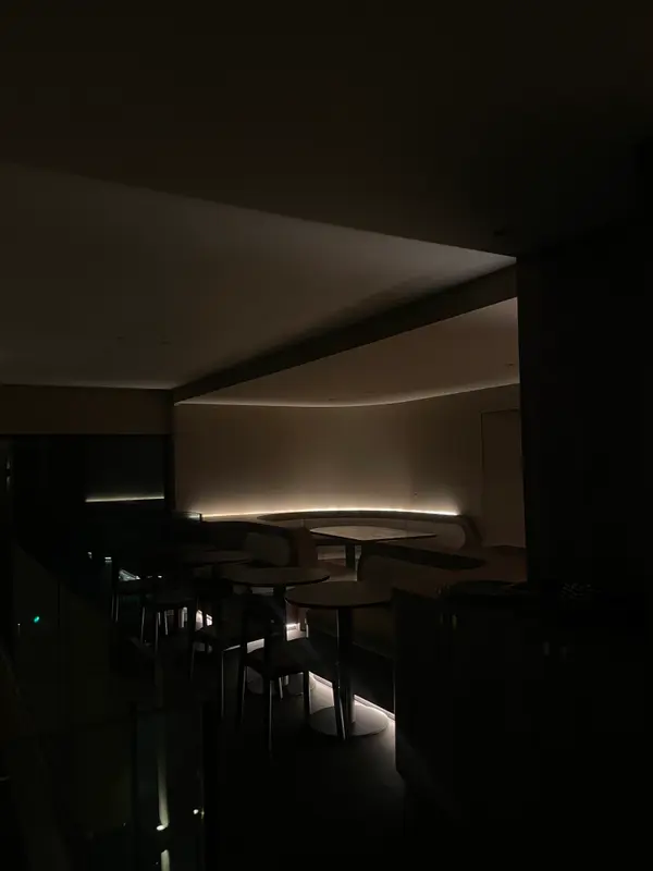 Dimly lit modern restaurant interior with curved booth seating, ambient LED lighting, and minimalist tables at night.